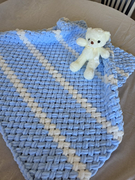 A handmade baby blanket in soft blue with white accents
